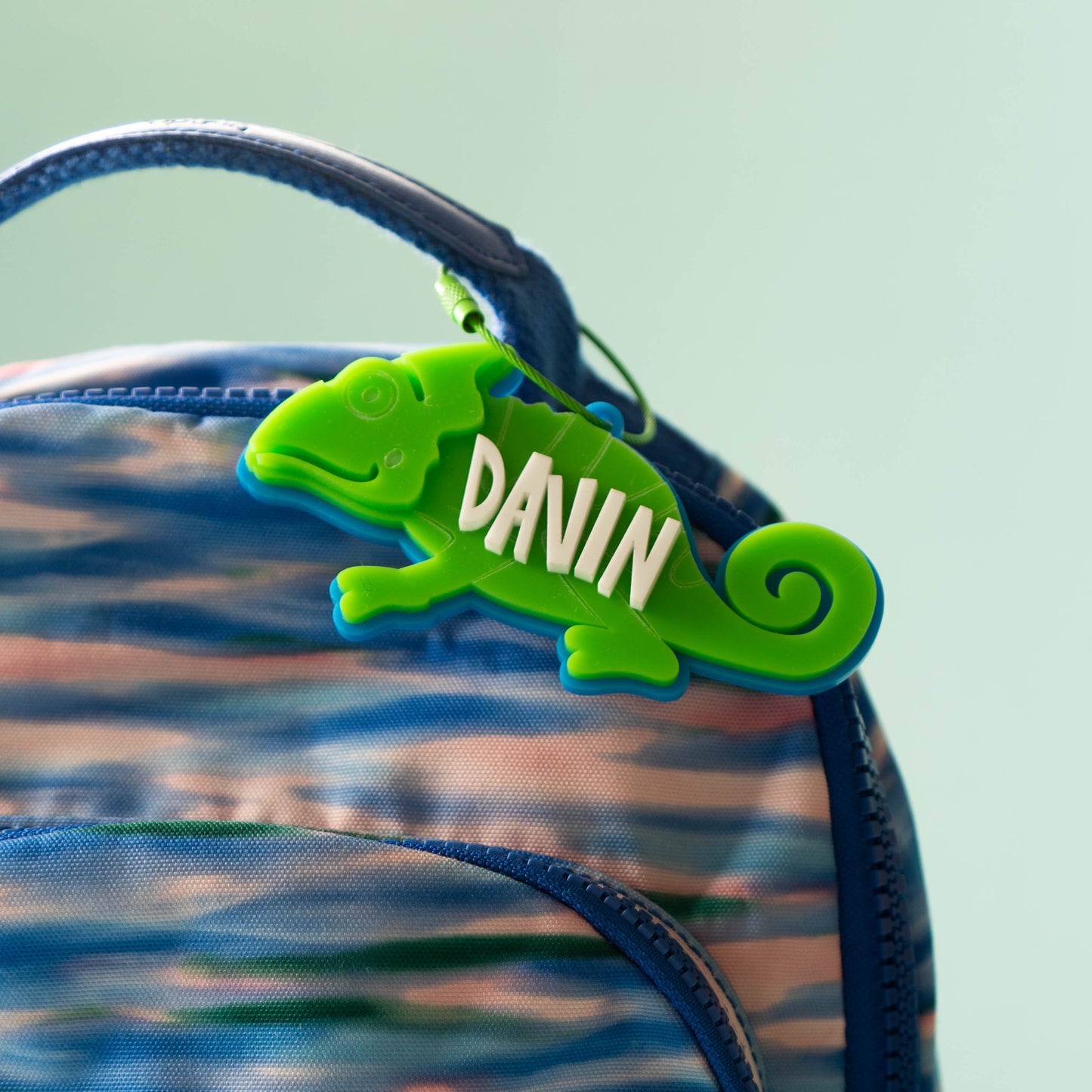 Bright green acrylic chameleon bag tag with custom white name text, laser cut and layered for kids’ backpacks.