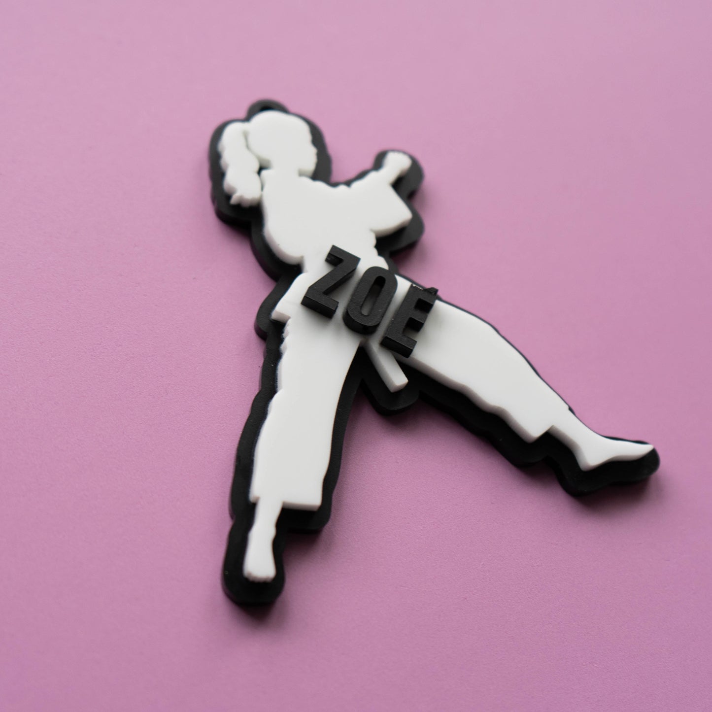 Custom karate girl bag tag with the name Zoe in layered acrylic on a pink background.