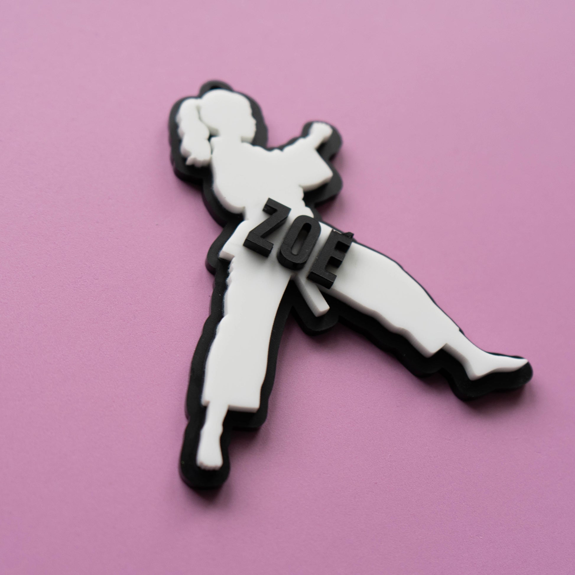 Custom karate girl bag tag with the name Zoe in layered acrylic on a pink background.
