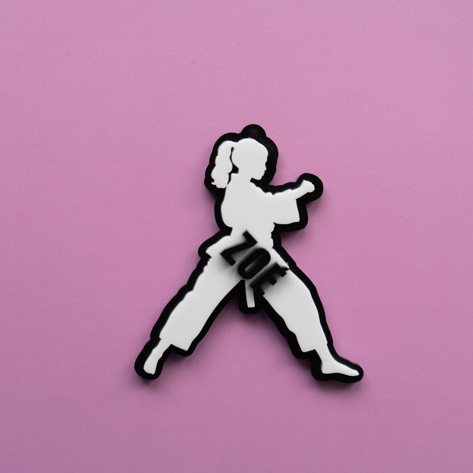 Custom karate girl bag tag with the name Zoe in layered acrylic on a pink background.