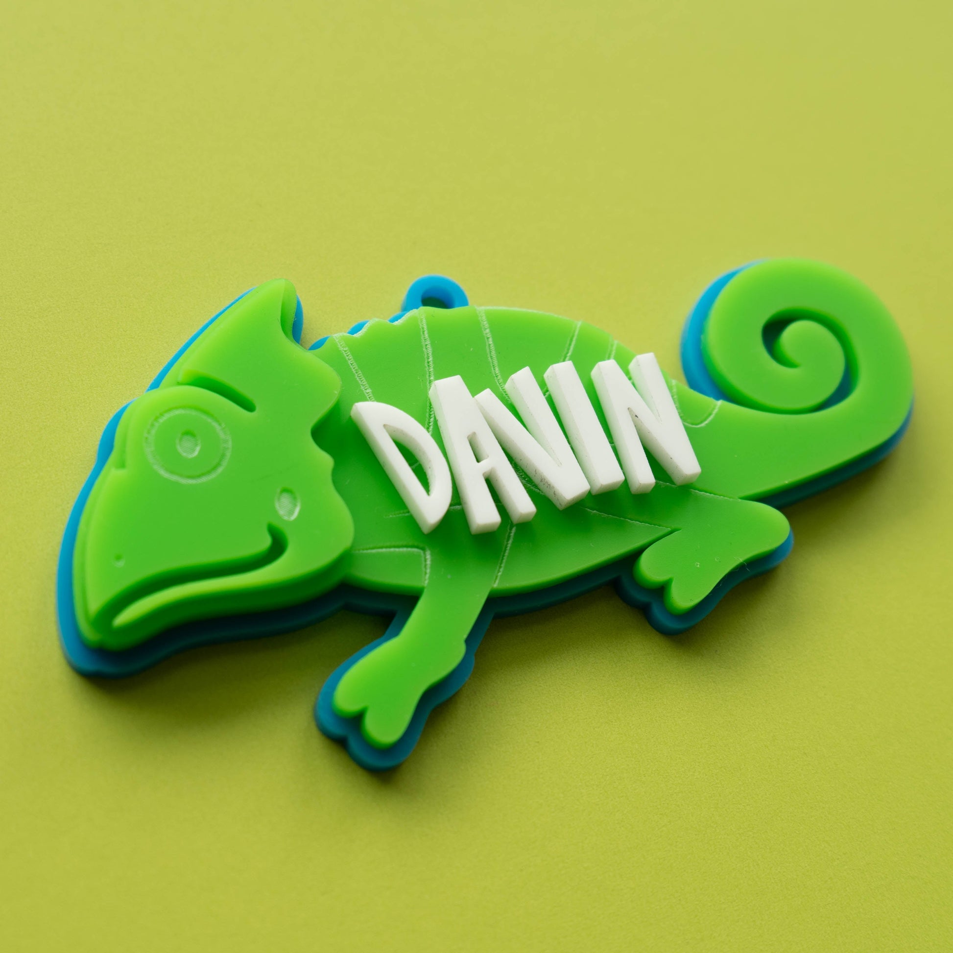 Bright green acrylic chameleon bag tag with custom white name text, laser cut and layered for kids’ backpacks.