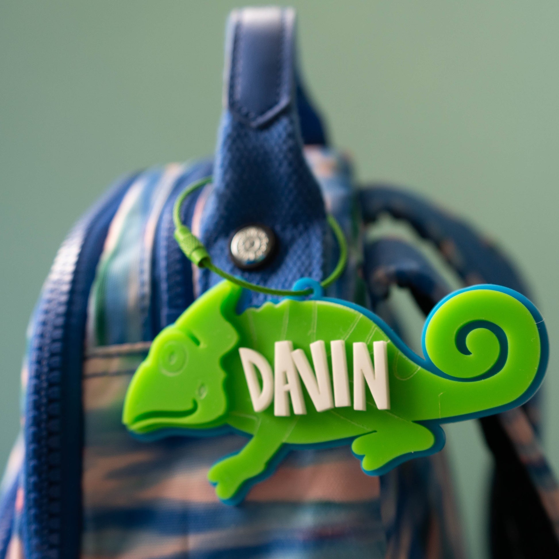 Bright green acrylic chameleon bag tag with custom white name text, laser cut and layered for kids’ backpacks.