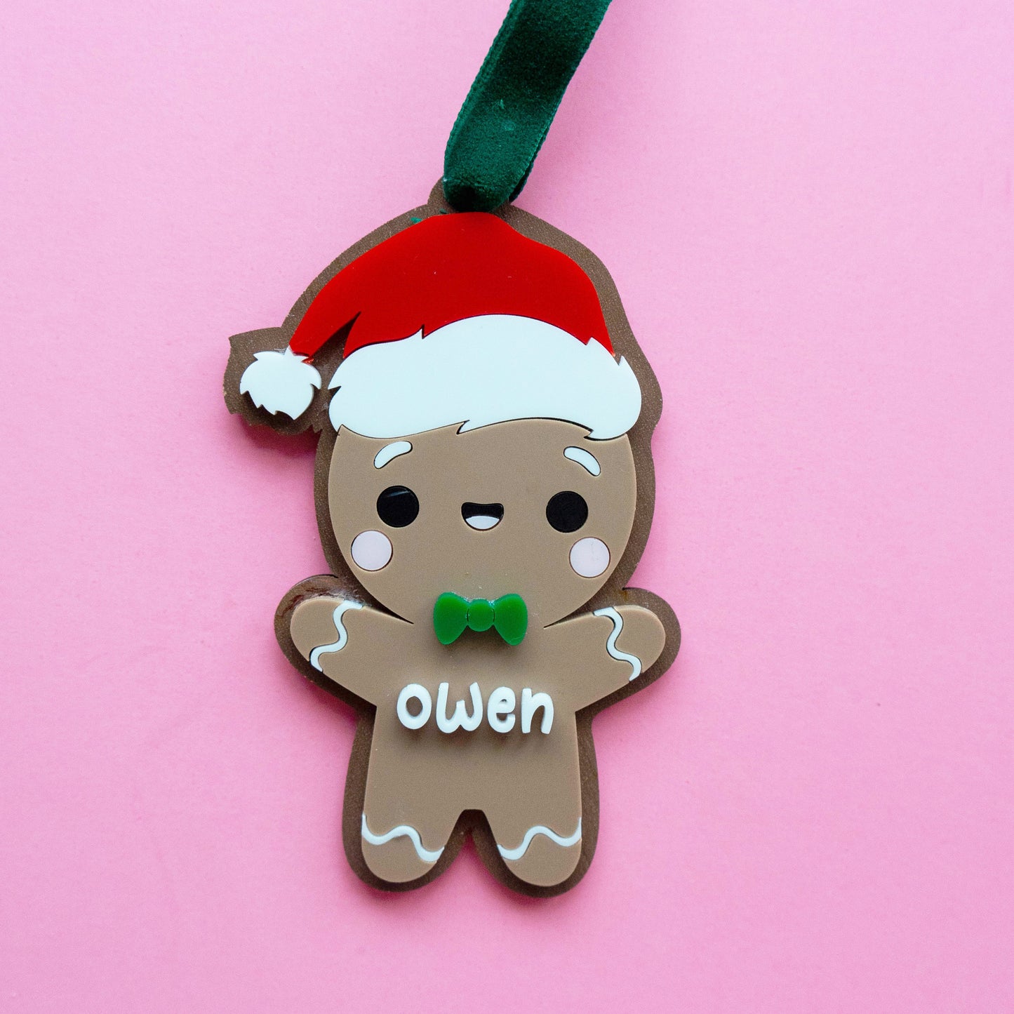 Gingerbread boy Christmas ornament made of layered acrylic with a Santa hat and custom name “Owen,” personalized ornament with Bible verse on the back.