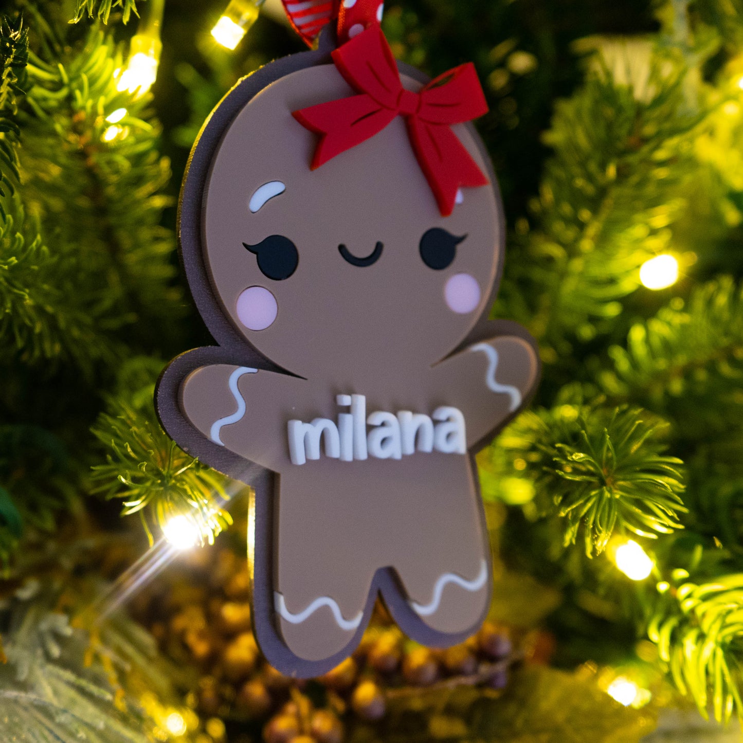 Custom name gingerbread girl ornament hanging on a lit Christmas tree.