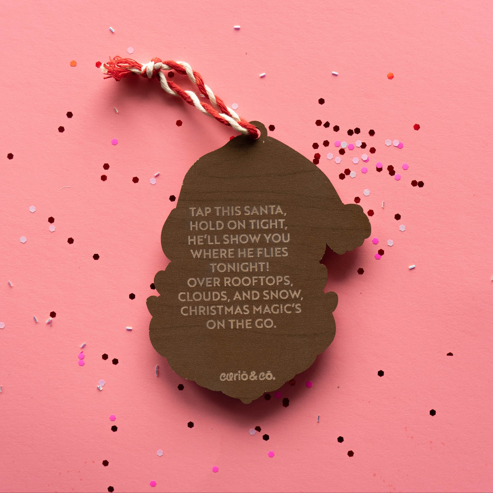 Acrylic Santa ornament with engraved rhyme on wood back on pink background with confetti — Curio & Co.