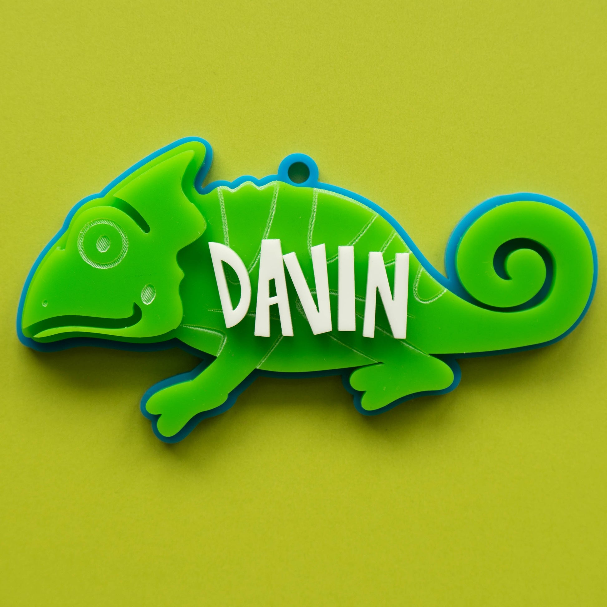Bright green acrylic chameleon bag tag with custom white name text, laser cut and layered for kids’ backpacks.