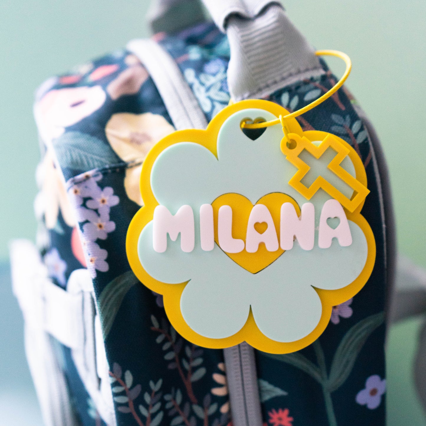 Floral-patterned bag with a 'MILANA' tag on a light blue background