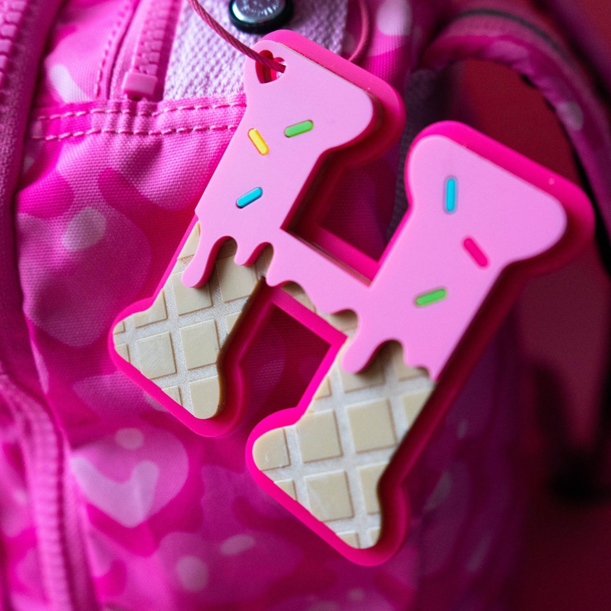 Pink ice cream cone-shaped keychain attached to a pink bag with a pink background