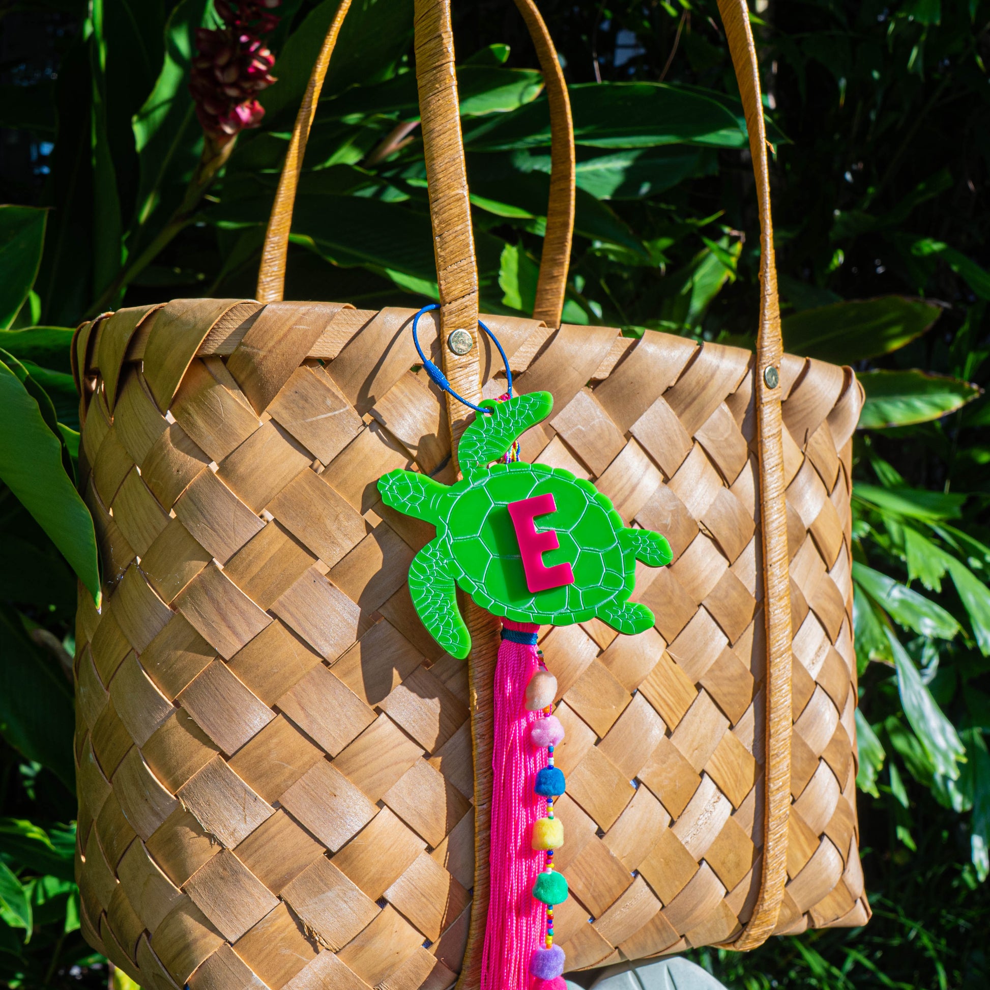 Personalized turtle bag tag attached to a kids’ backpack, layered green acrylic with bold pink initial, ocean-inspired accessory.