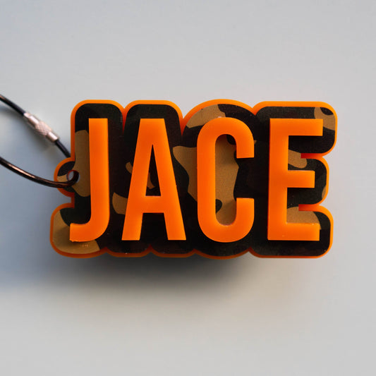 Personalized camo acrylic name tag featuring the name “Jace” in bold orange lettering with a camouflage background.
